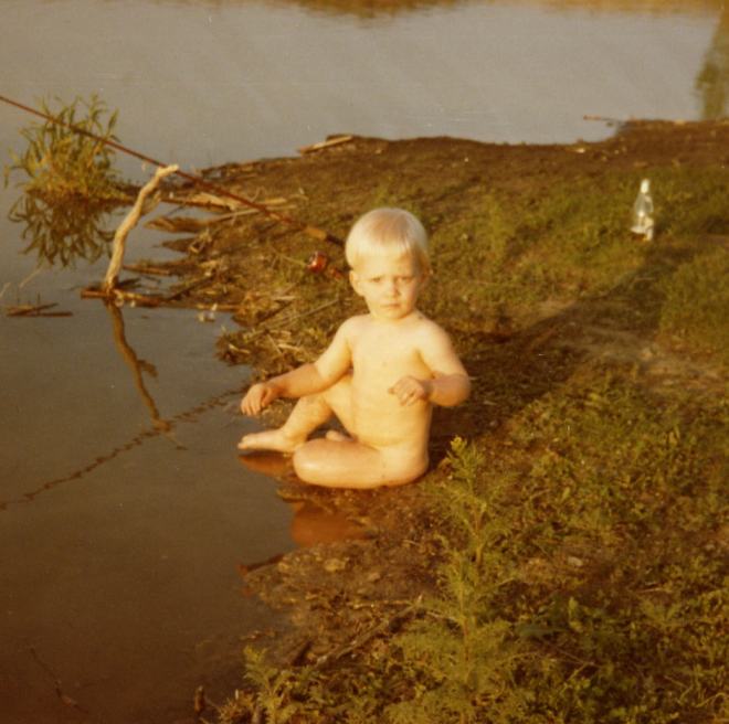 Naked Paul Ross sitting in lake at camera